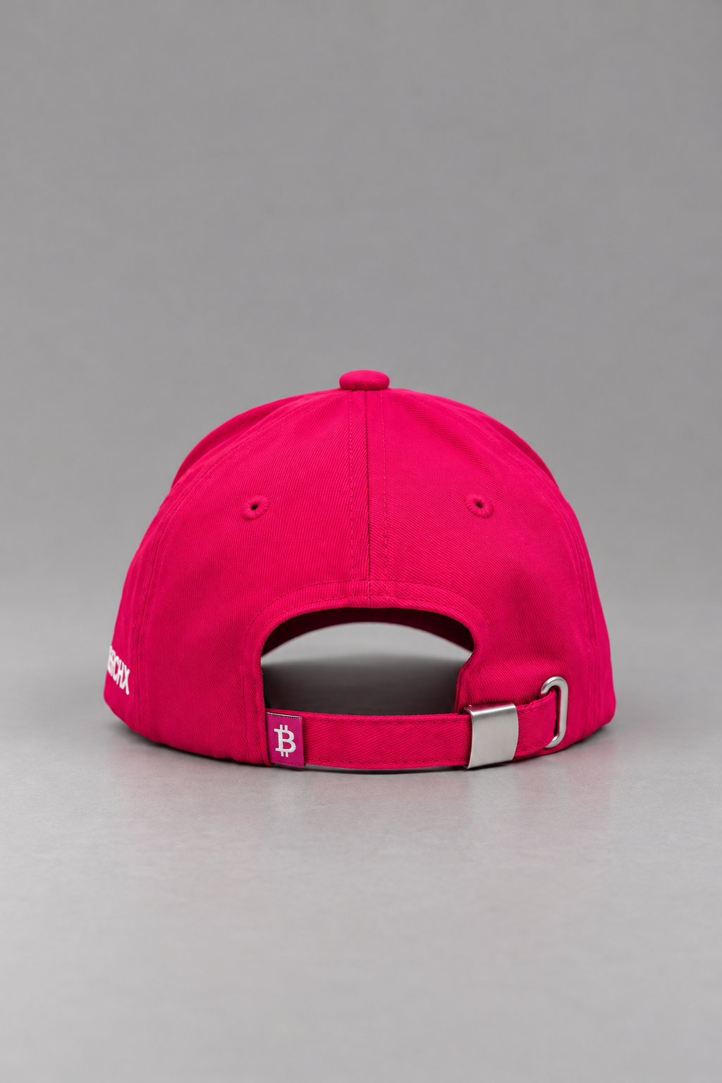 Rear view of Merch IX hot pink Bitcoin baseball cap featuring an adjustable fabric strapback, silver metal buckle, and white Bitcoin logo woven tag.