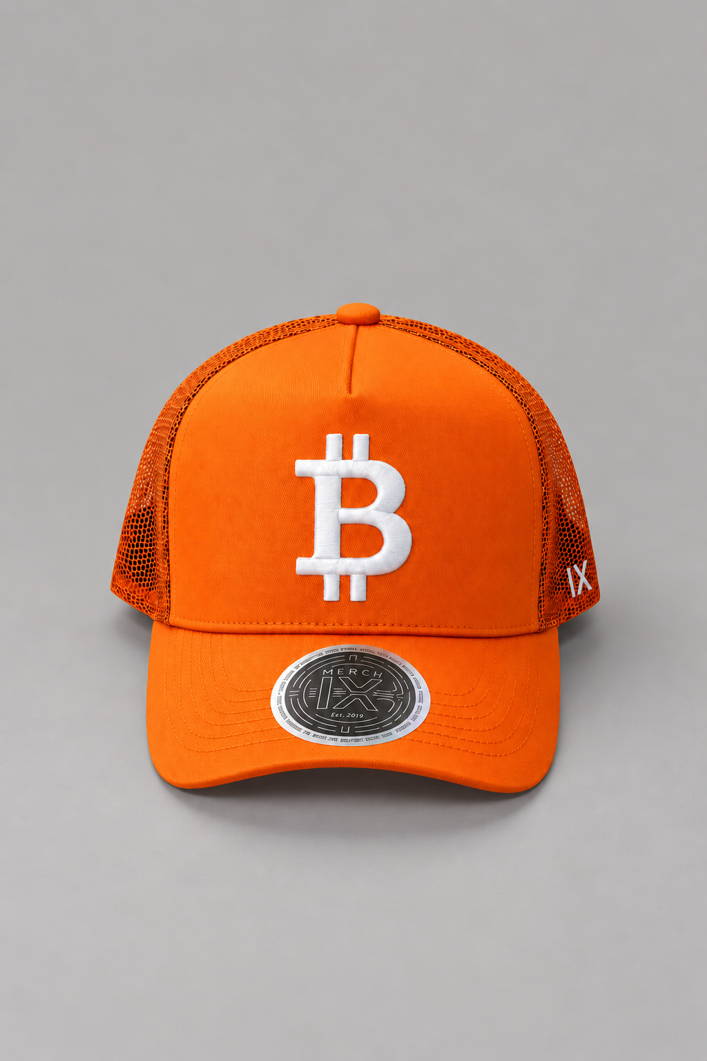 Front view of MERCH IX orange Bitcoin trucker hat featuring raised white Bitcoin embroidery, breathable orange mesh panels, white IX side branding, curved brim, and metallic silver visor sticker.